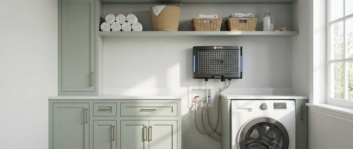 OxiOrg O³ Pro above the washer in a sage green laundry room, hoses running to the washer box