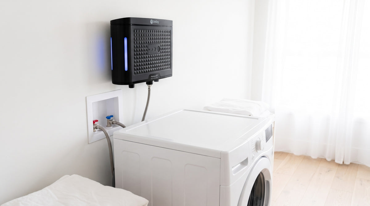 OxiOrg O3 Pro on the wall above the washer, its light glowing blue