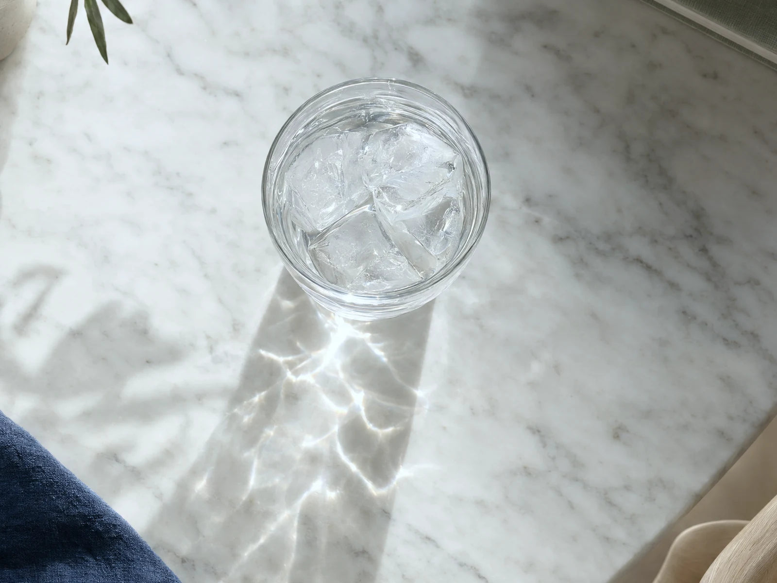 A glass of clear water with ice on a white marble table