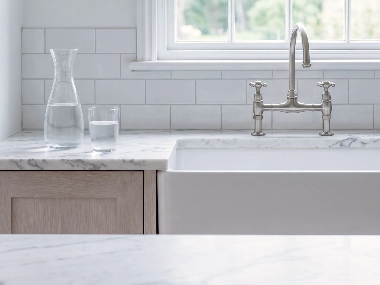A carafe and a glass of water beside a classic farmhouse sink