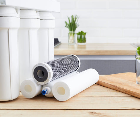 Multi-stage reverse osmosis system with replacement sediment and carbon cartridges staged on a light wood kitchen counter