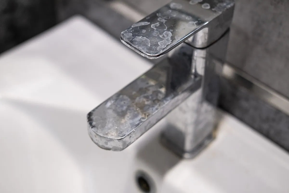 water faucet with white chalky limescale spots from hard water minerals