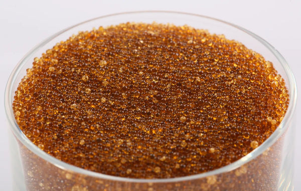 Close-up of amber ion exchange resin beads in a glass dish