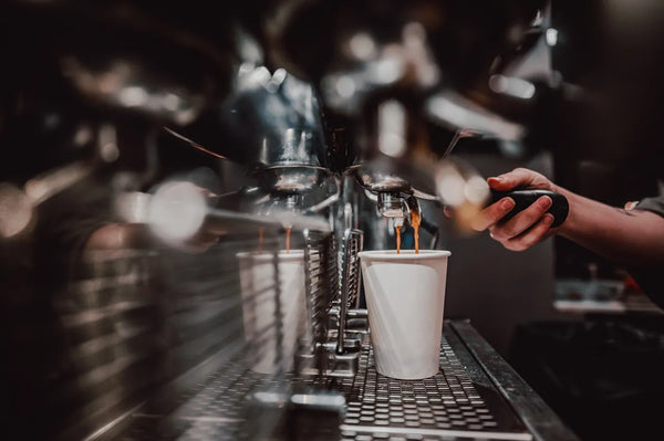 Barista pulling an espresso shot on a commercial coffee machine in a cafe