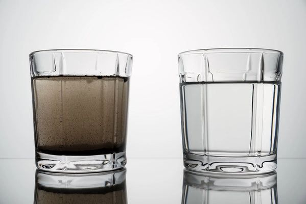 A glass of cloudy, sediment-filled tap water beside a glass of clean filtered water