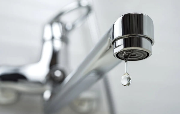 Chrome faucet aerator releasing a single slow water drop, illustrating slow reverse osmosis water flow and low RO system pressure