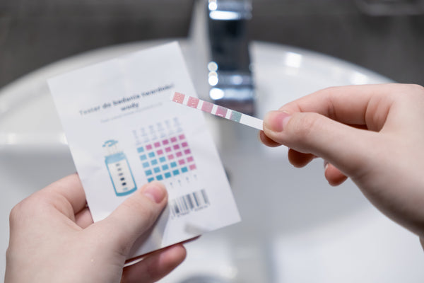 hand holding a water hardness test strip to assess water hardness levels