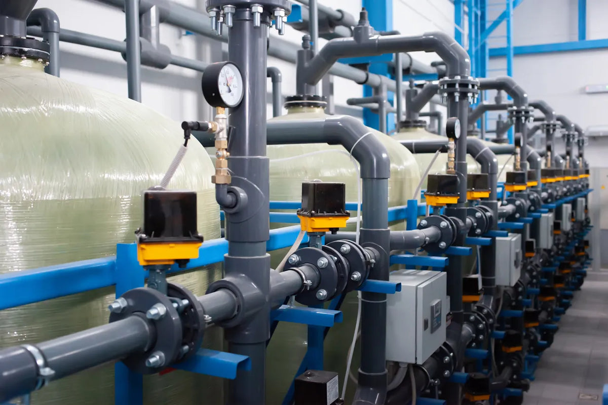 Row of commercial water softener and filtration tanks with valves in a hotel mechanical room
