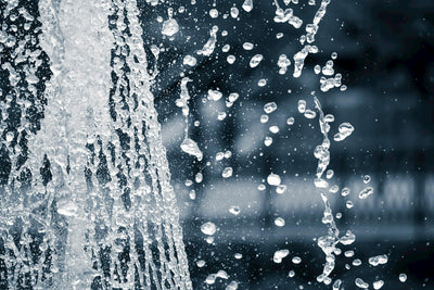 Clean water droplets splashing against a dark background, illustrating the different types of drinking water