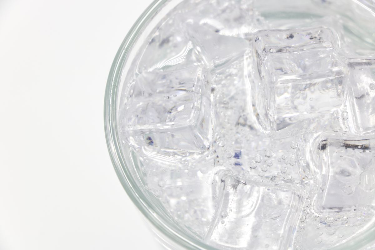Top-down view of a drinking glass filled with clear water and ice cubes