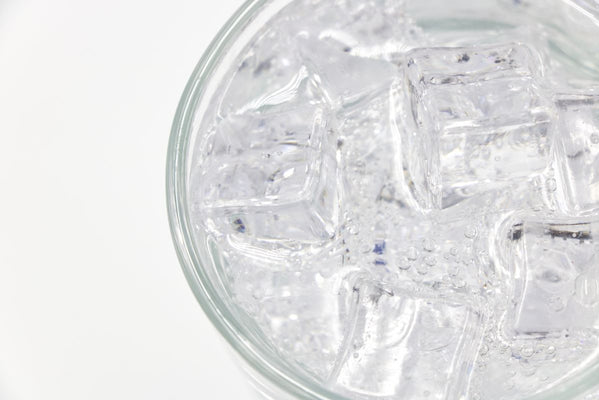 Top-down view of a drinking glass filled with clear water and ice cubes