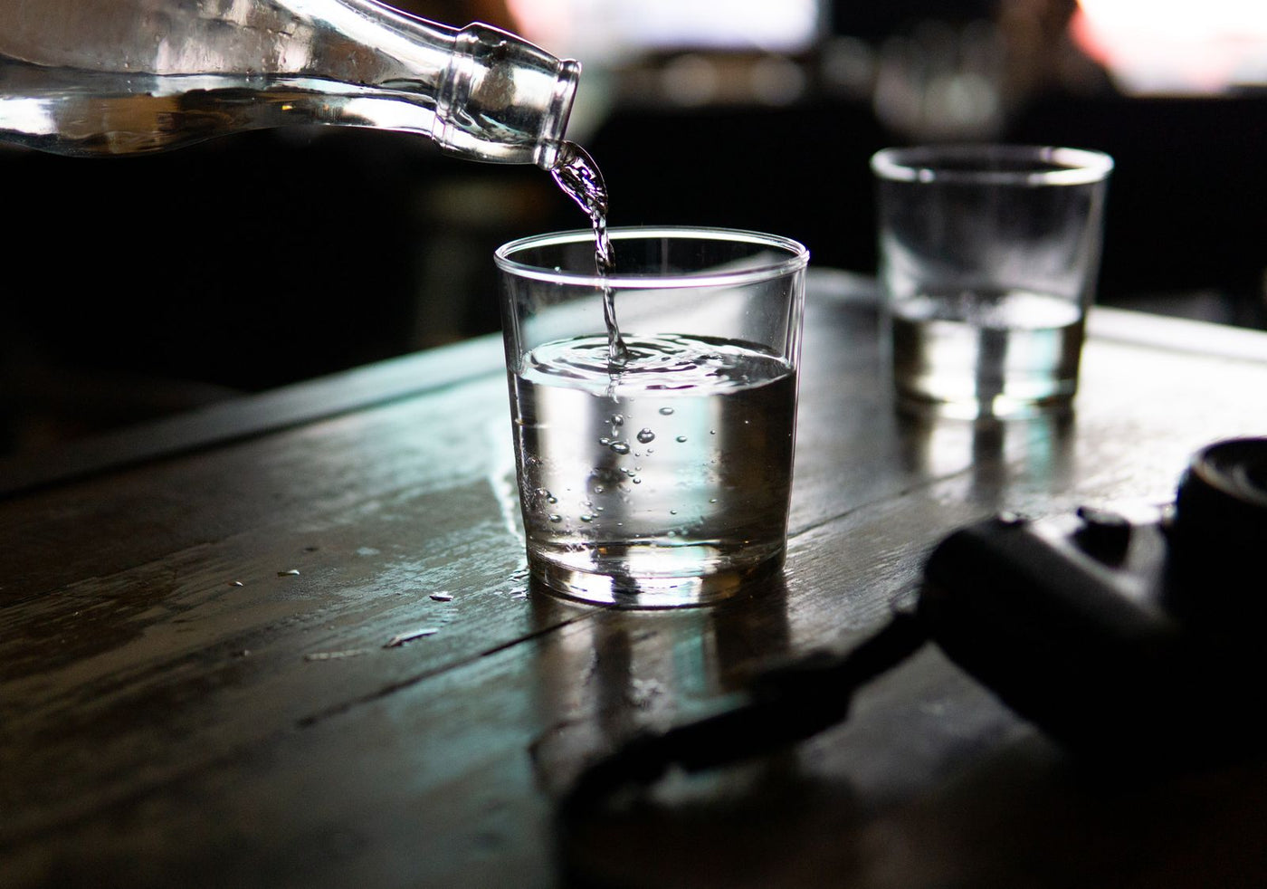 Clear water being poured into a drinking glass on a kitchen table