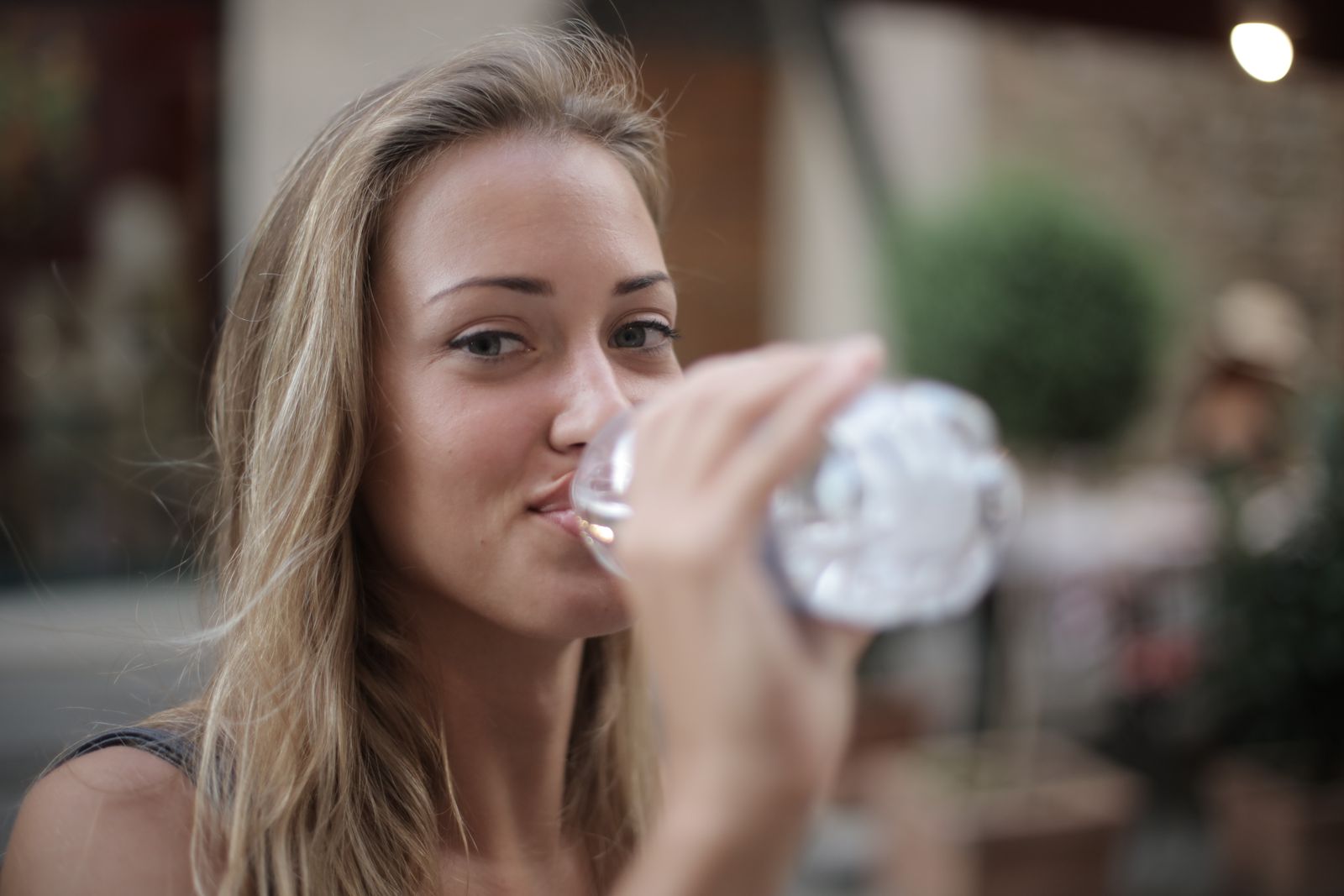 Woman drinking bottled water outdoors on a sunny day