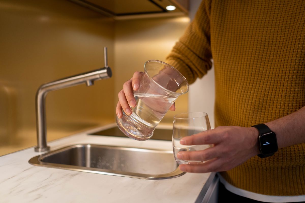 Person filling a drinking glass with water at a home kitchen tap