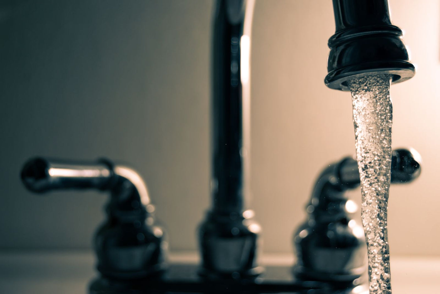 Water running from a chrome kitchen faucet, where copper can leach into tap water from household plumbing