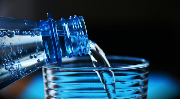 Clean, sugar-free water being poured from a bottle into a clear glass