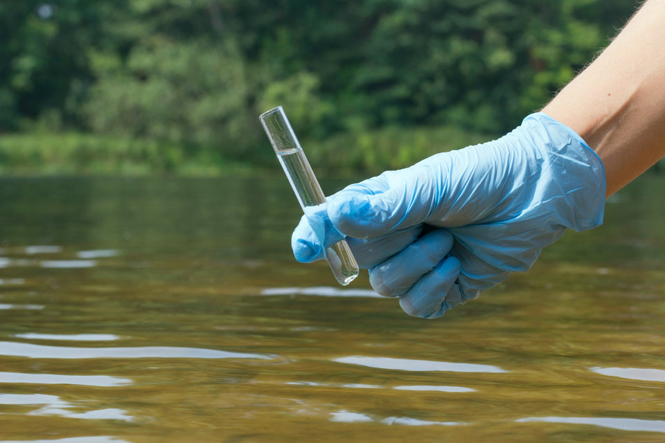Water testing vial held up to light, showing a clear sample for well water testing.