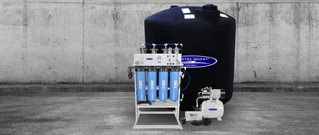 Water filtration system with a large tank against a concrete wall.