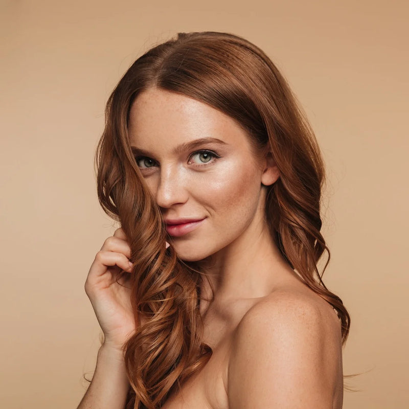 Woman with long, wavy auburn hair against a beige background