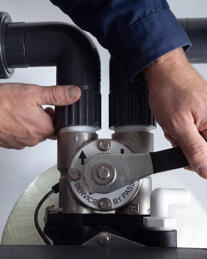 A plumber turning the bypass valve on a Crystal Quest system to service