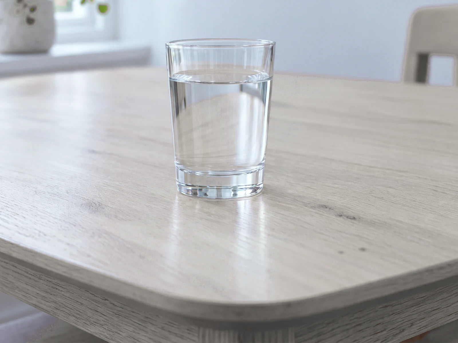 A glass of water on a dining table by a window